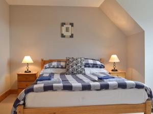 a bedroom with a blue and white bed with two lamps at Taigh an Tuath in Isleornsay