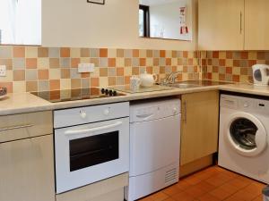 een keuken met een wasmachine en een wasmachine bij Cherrytree Cottage - 29937 in Holcombe Burnell