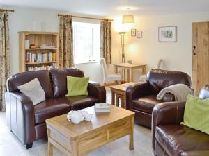 a living room with two leather couches and a coffee table at Herons Weir in Buckland Dinham