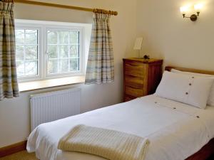 a bedroom with a white bed and a window at Herons Weir in Buckland Dinham