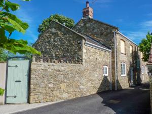 an old stone building with a gate and a door at Herons Weir in Buckland Dinham