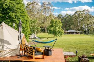 a hammock and a tent in a field at Unwind Escapes Cabins & Glamping in Dooralong