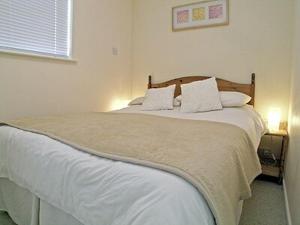 a bedroom with a large bed with white sheets and pillows at Brightlands Apartment in Poughill