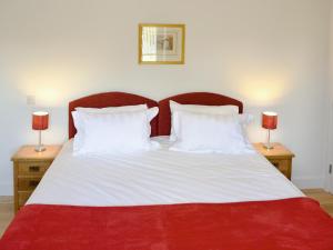 a red and white bed with two lamps on tables at The Hayloft - Nab in Aynho