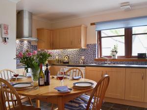 cocina con mesa de madera y copas de vino en Bethany Cottage, en Aberfoyle