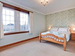 sypialnia z łóżkiem i 2 oknami w obiekcie The Cottage w mieście Girvan