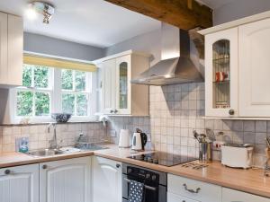 a kitchen with white cabinets and a sink at Dove Cottage in Middleham