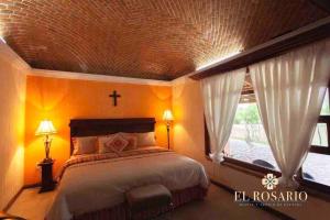 ein Schlafzimmer mit einem Bett mit einem Kreuz an der Decke in der Unterkunft Quinta El Rosario maravilloso lugar in Lagos de Moreno