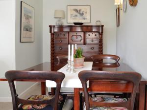 a dining room table with two chairs and a dresser at Weavers Cottage in Stow on the Wold
