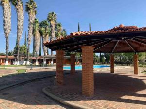 a pavilion in a park with a pool and palm trees at Quinta El Rosario maravilloso lugar in Lagos de Moreno