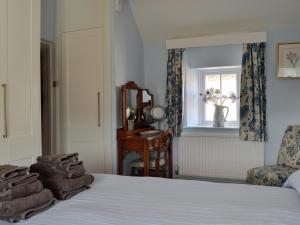 a bedroom with a bed and a window and a chair at Weavers Cottage in Stow on the Wold