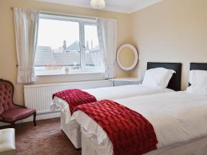 een slaapkamer met 2 bedden, een raam en een stoel bij The Beach Hut in Bridlington