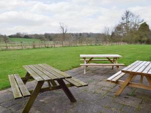 two wooden picnic tables sitting on a brick patio at The Coach House in Somersal Herbert