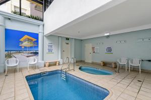 una piscina en una habitación con sillas y una piscina en Pelican Sands Beach Resort en Gold Coast