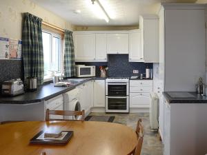 uma cozinha com armários brancos e uma mesa de madeira em Horsemans em John o' Groats
