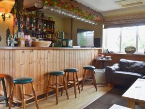 - un bar avec tabourets et un canapé dans la chambre dans l'établissement Poplar Cottage, à Cote