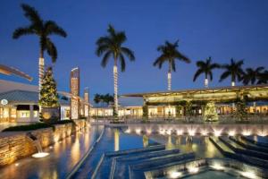 a pool in front of a building with palm trees at Naples Dream at WTC with Heated Pool SPA Sauna 7 bicycles and 3 mls to beach in Naples