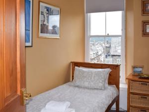 ein kleines Schlafzimmer mit einem Bett und einem Fenster in der Unterkunft Lake View Apartment in Bowness-on-Windermere