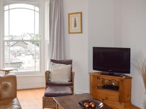 ein Wohnzimmer mit einem Flachbild-TV und einem Stuhl in der Unterkunft Lake View Apartment in Bowness-on-Windermere