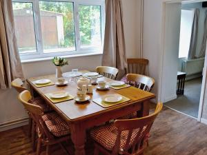 a dining room table with chairs and a wooden table with dishes at Mill Cottage in Winterborne Steepleton