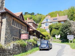 an old blue car driving down a street next to a building at Church View in Lynmouth