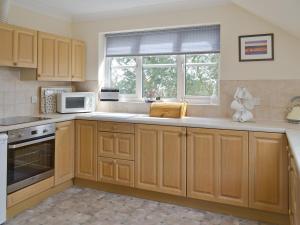 a kitchen with wooden cabinets and a microwave and a window at Tamar View in Saltash