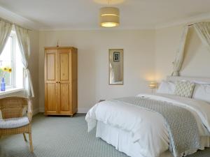 1 dormitorio con 1 cama blanca grande y 1 silla en Tamar View, en Saltash