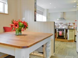 un jarrón de flores sobre una mesa en una cocina en The Old Sweet Shop, en Hook Norton