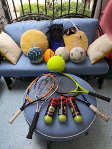 a table with tennis rackets and balls on a couch at Naples Dream at WTC with Heated Pool SPA Sauna 7 bicycles and 3 mls to beach in Naples