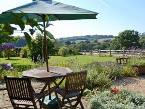 a wooden table with an umbrella in a garden at The Dairy in Ninfield