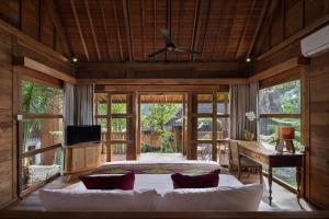 a bedroom with a bed and a desk and a television at RUMAH KAYU RESORT in Ubud