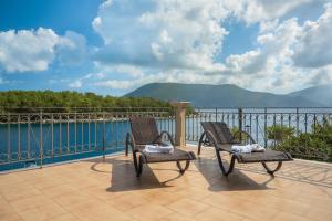 a patio with two chairs and a view of the water at Captain's Quarters at Fiscardo Waterfront-feel the breeze in Fiskardho