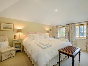 a bedroom with a large white bed and a chair at The Stables At Weedon Hill Farm in Church Stowe