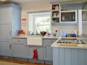 een keuken met blauwe kasten, een wastafel en een raam bij Belle Vue-ukc778 in Eggleston