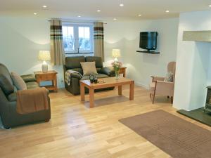 a living room with a couch and a tv at Home Park Farm Cottages A in Lanteglos