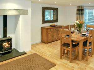 a kitchen and dining room with a table and a wood stove at Home Park Farm Cottages A in Lanteglos