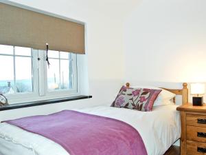 a bedroom with a bed and a window at Home Park Farm Cottages A in Lanteglos