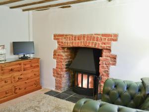 a living room with a brick fireplace and a television at Rose Cottage in Hythe