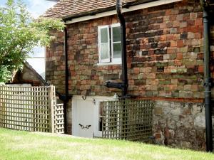 una casa de ladrillo con una puerta blanca y una valla en Rose Cottage en Hythe