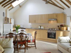 a kitchen with a dining room table and a kitchen with wooden cabinets at Dove Cottage - 25117 in Flamborough