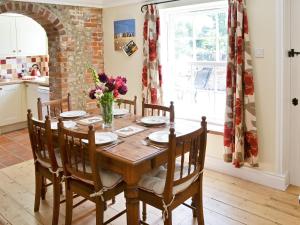 a dining room table with chairs and a vase of flowers at South View Cottage in West Beckham