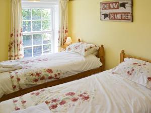 two twin beds in a bedroom with a window at South View Cottage in West Beckham