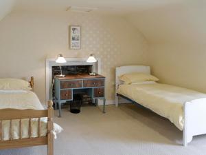 a bedroom with two beds and a desk with a mirror at Burnfoot Of Cluden in Holywood