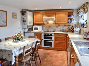 a kitchen with wooden cabinets and a table with chairs at The Coach House in Chideock