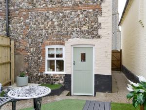 a door in the side of a brick building with a table at Time Cottage in Coltishall