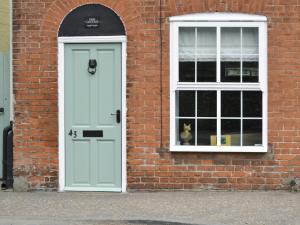 a white door and a dog in a window at Time Cottage in Coltishall