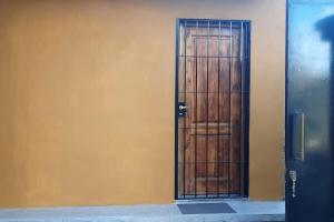una puerta de madera con una puerta de metal en una pared amarilla en Mono ambiente Loria en Luján de Cuyo