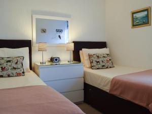 a bedroom with two beds and a night stand with a radio at Squirrel Cottage in Windermere