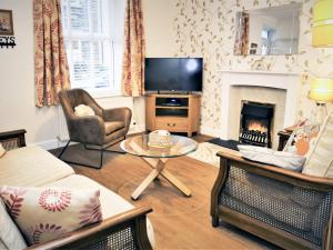 a living room with a fireplace and a tv at Squirrel Cottage in Windermere