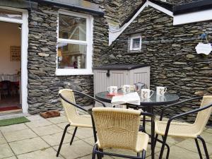 a table and chairs on a patio with a stone wall at Squirrel Cottage in Windermere